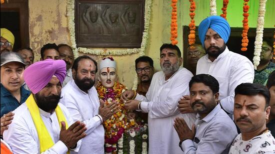 A commemoration at a memorial bust of Sukhdev Thapar with a relief plaque of three martyrs behind it