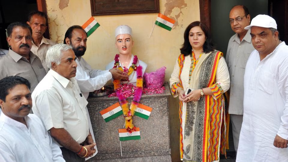 People gathered around a garlanded bust of Sukhdev Thapar at the ancestral family house in Naughara, Ludhiana